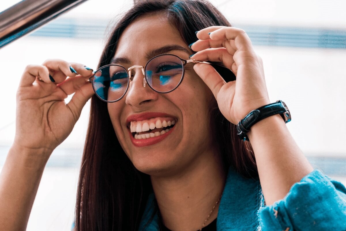 A young woman trying on glasses and smiling