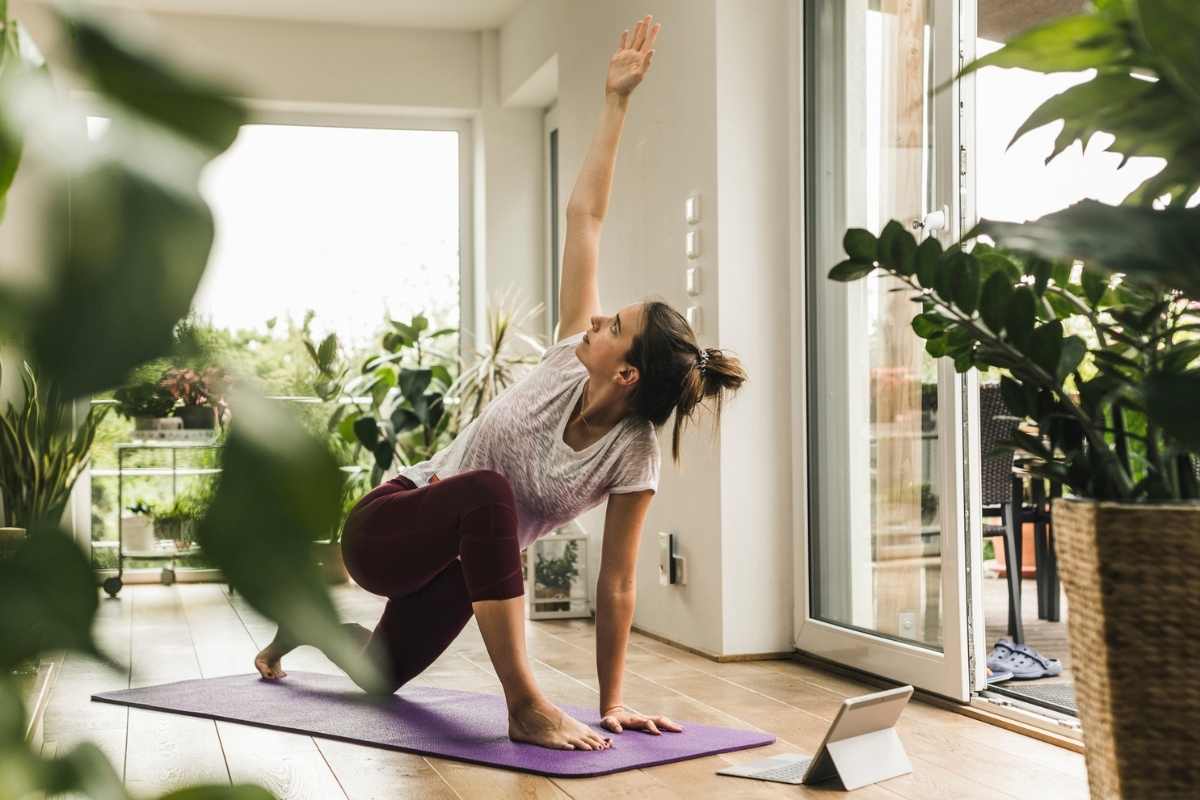 A young woman practising yoga in a sunny room with plants