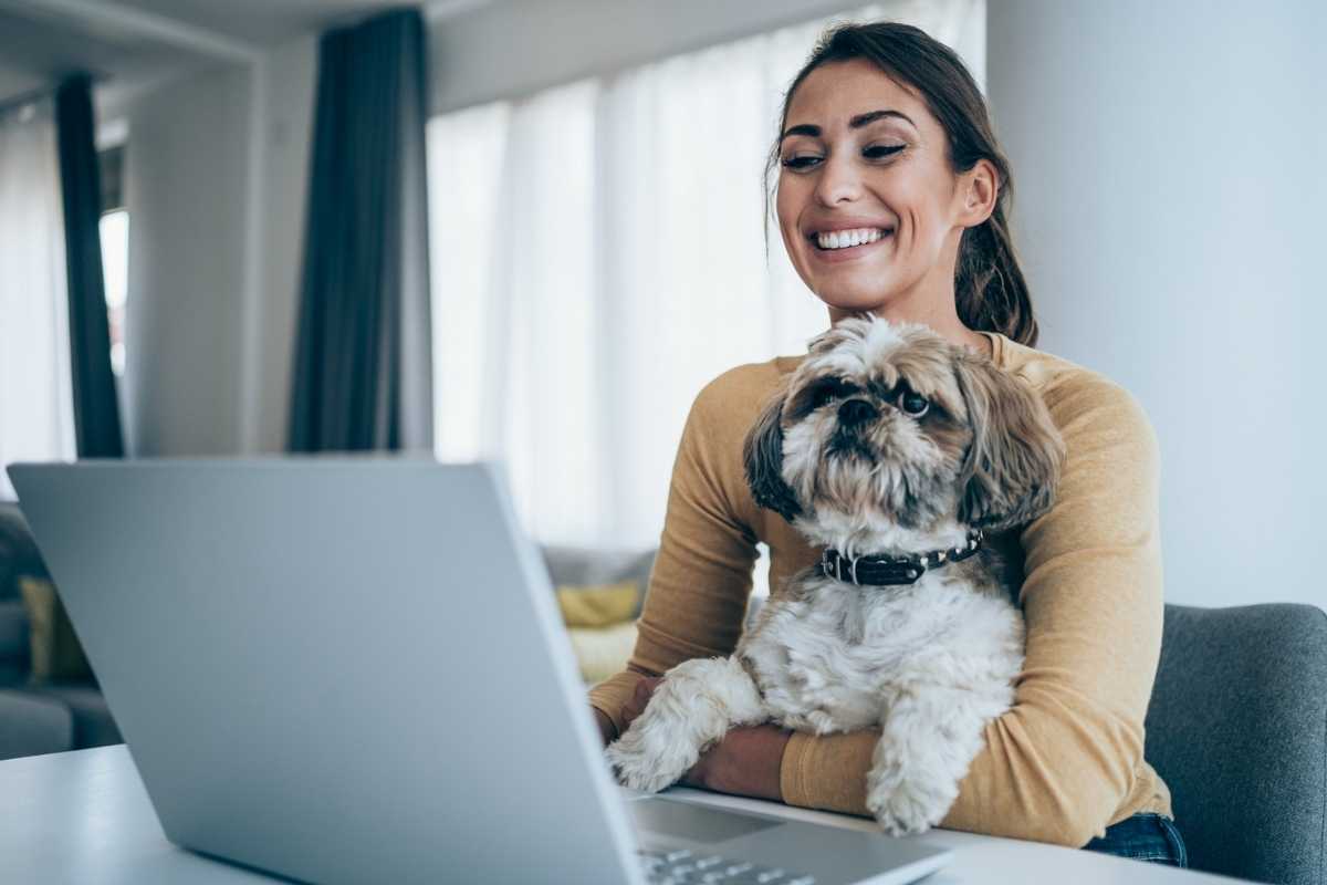 A young woman on a telehealth video call with a dog on her lap