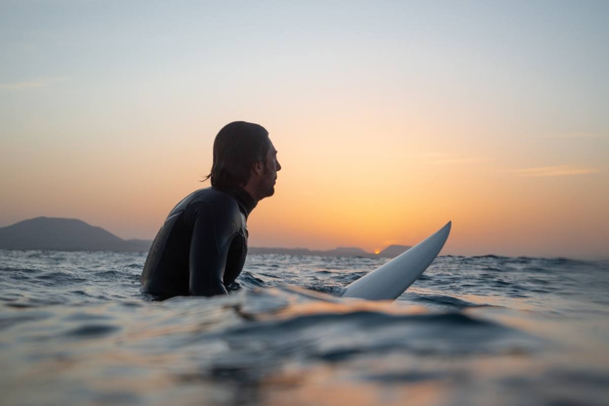 man in ocean on surfboard thinking