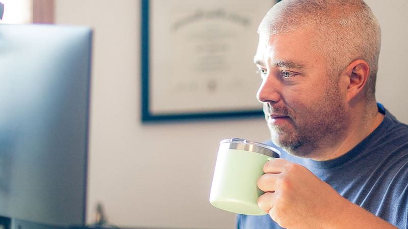 Man drinking coffee on computer