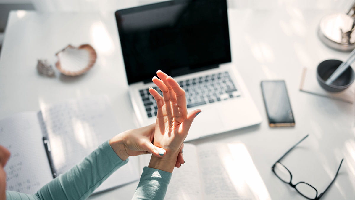 Person holding hand in front of laptop