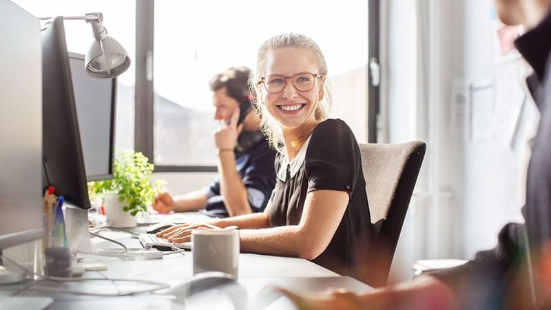 Young corporate woman smiling at desk