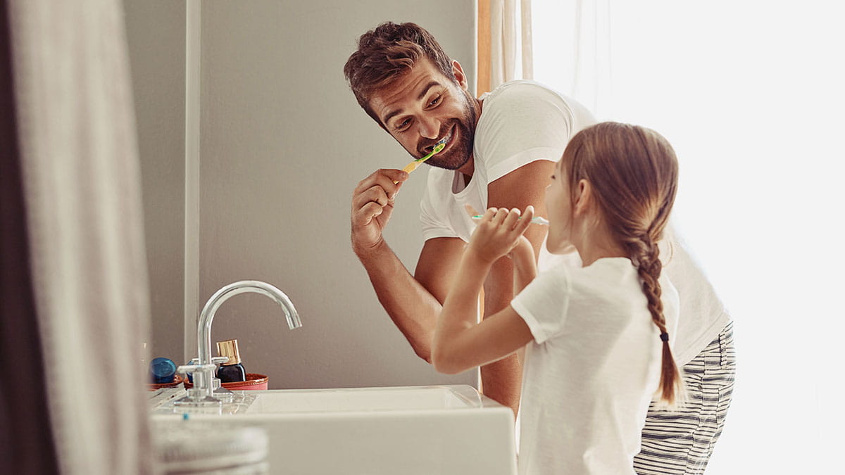 Man brushing teeth with young girl