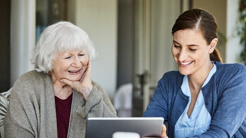 Woman showing elderly lady iPad