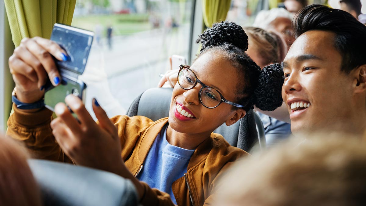 Young couple on bus looking at phone