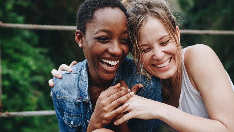 Two young woman laughing and hugging