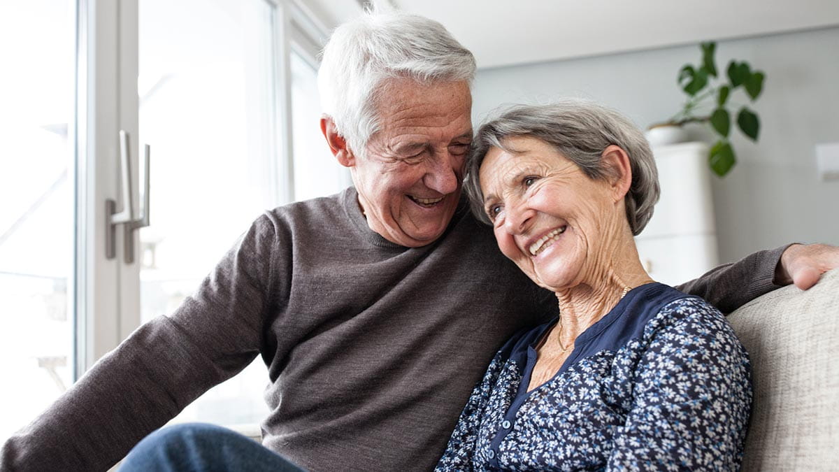 Retired couple smiling on couch