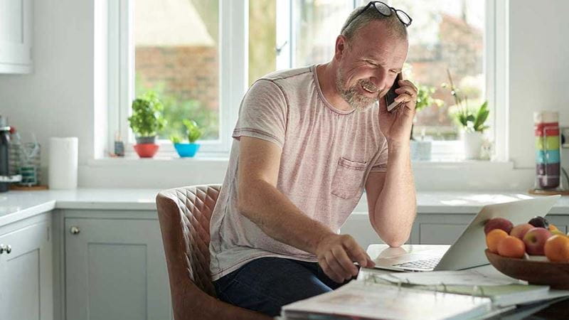 Man sitting in kitchen on phone