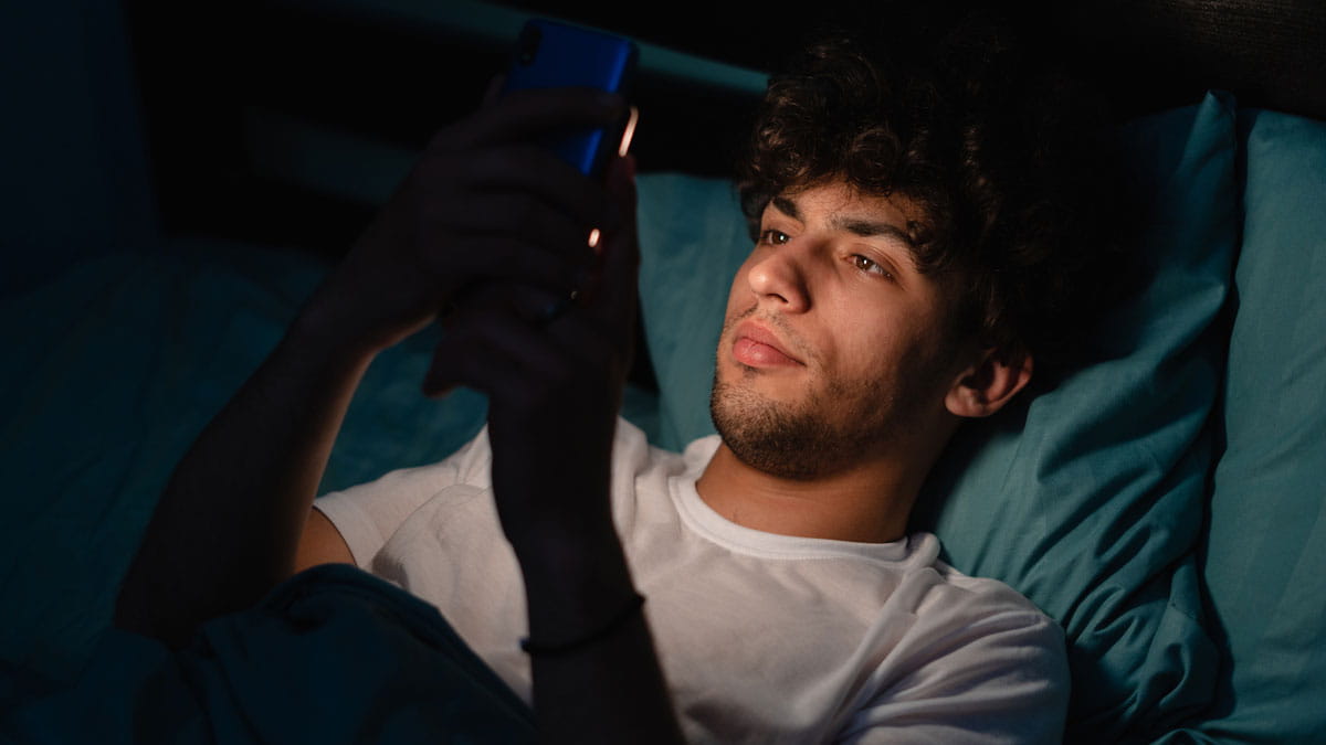 A man scrolling through his phone at night