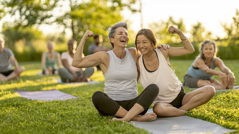 Two smiling women stretching