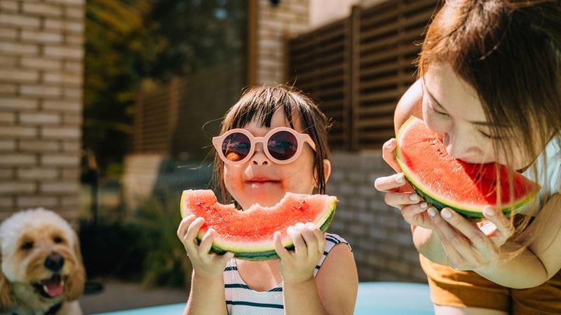 Young girl eating watermelon and wearing sunglasses