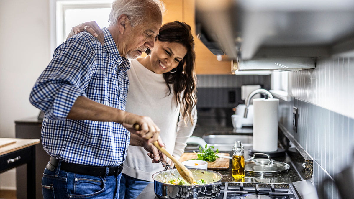 Middle-aged couple cooking at stove