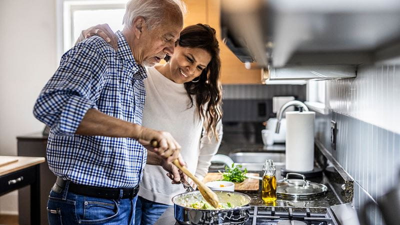 Middle-aged couple cooking at stove
