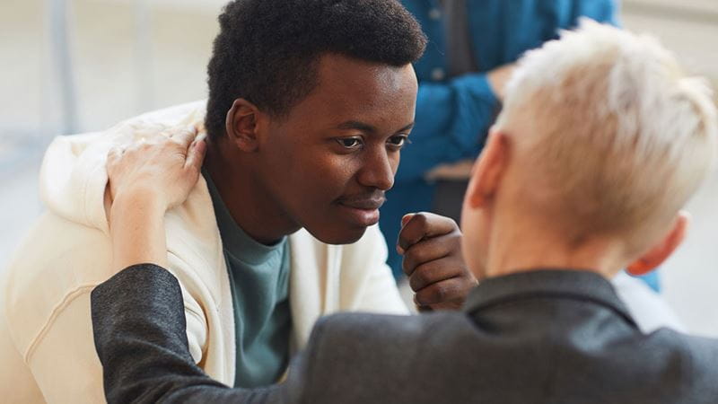 Two people chatting with hand on shoulder