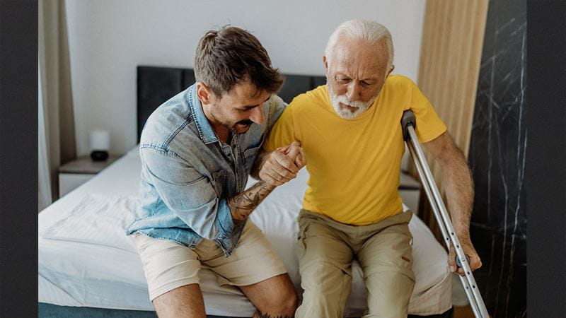 Man helping elderly man out of bed