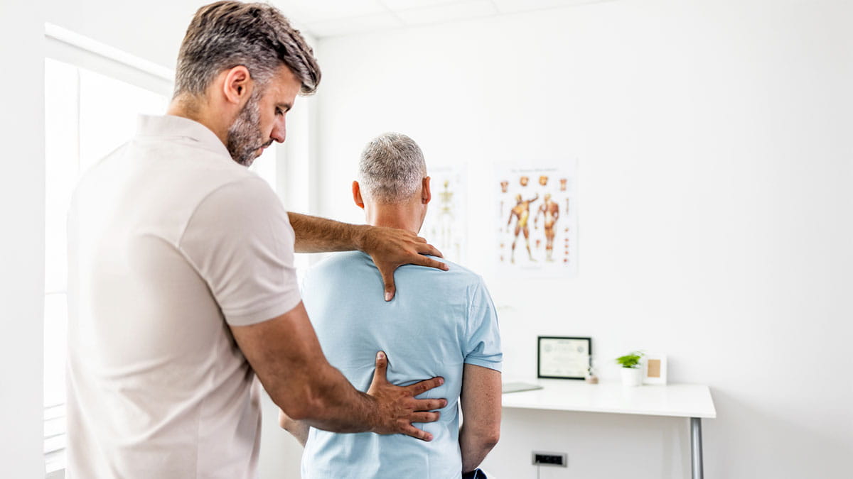 Older man having his back assessed by doctor