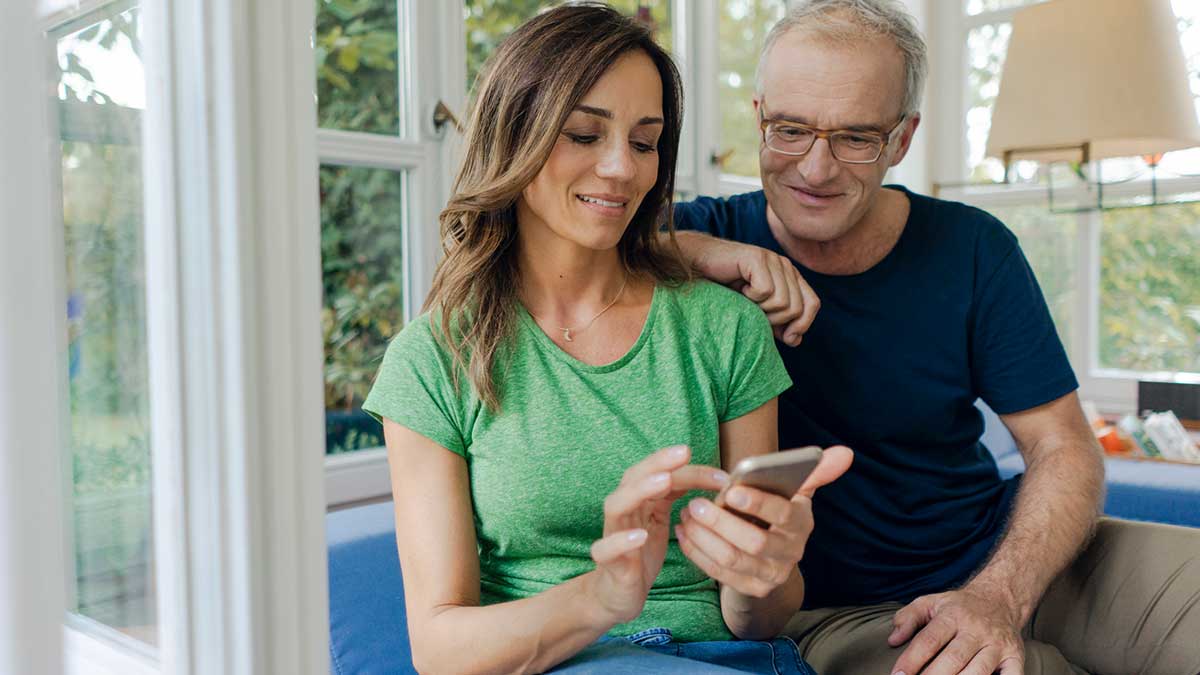 A couple in their house browsing a mobile phone