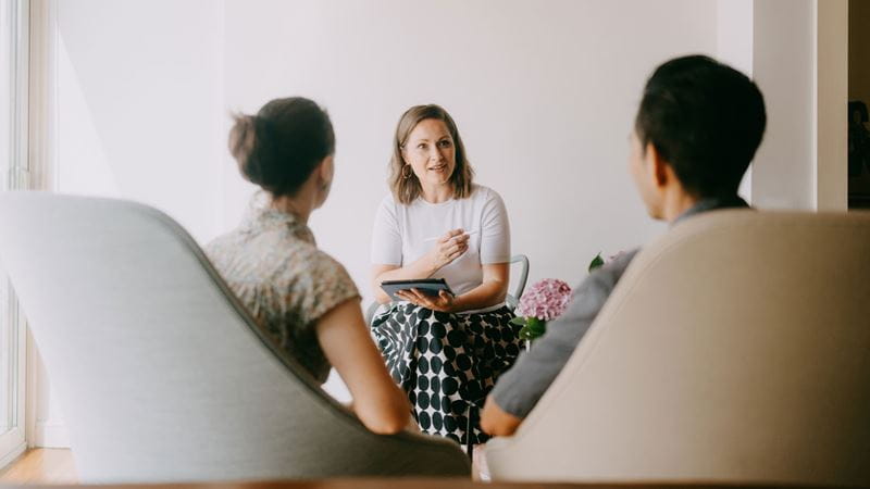 Counsellor speaking with two clients during a counselling session focused on mental wellbeing and emotional support