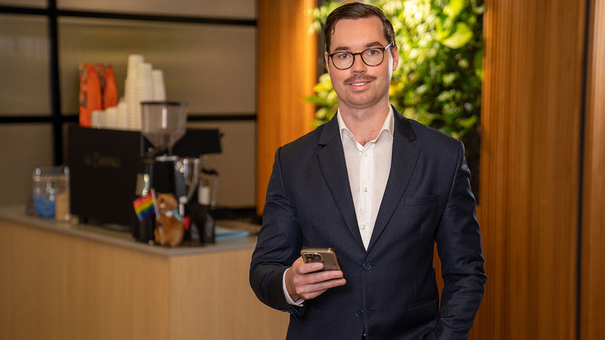 HBF employee using a mobile phone in Perth office after developing a coffee ordering app through a Bold Goal.