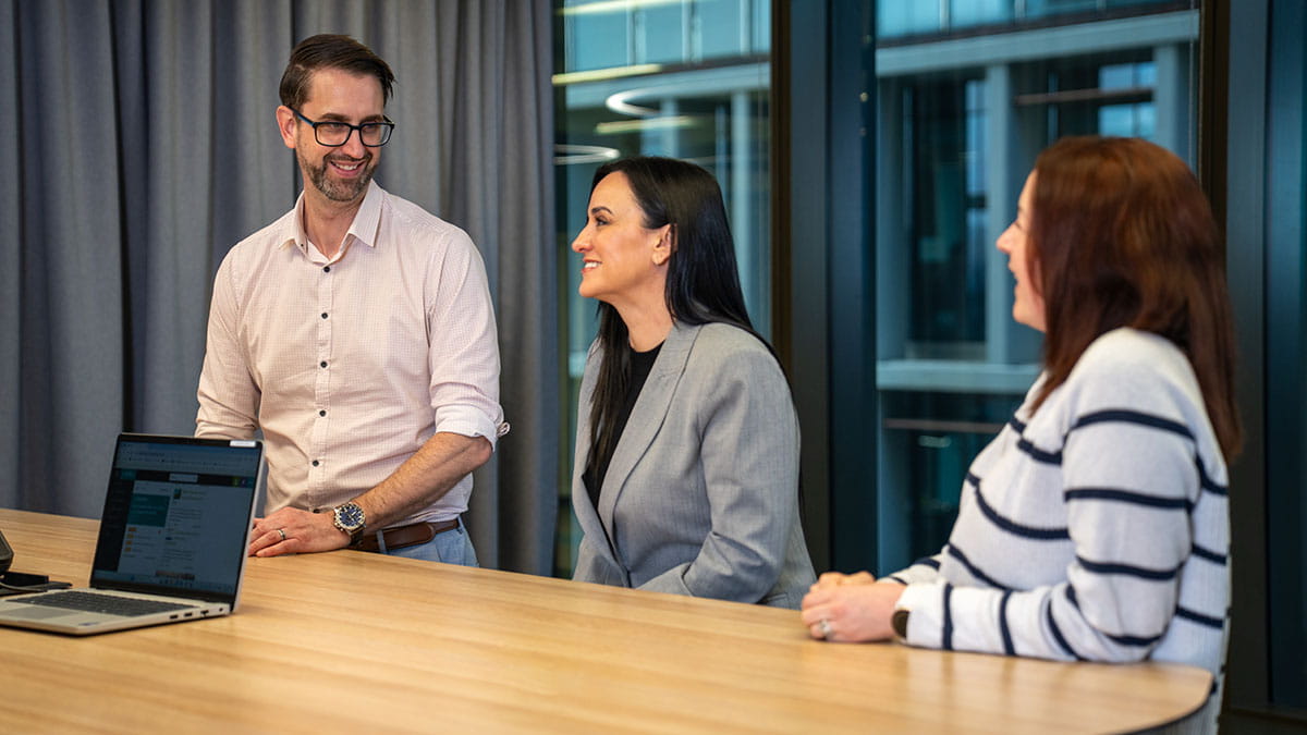Employees discussing work around a meeting table in an HBF office environment.