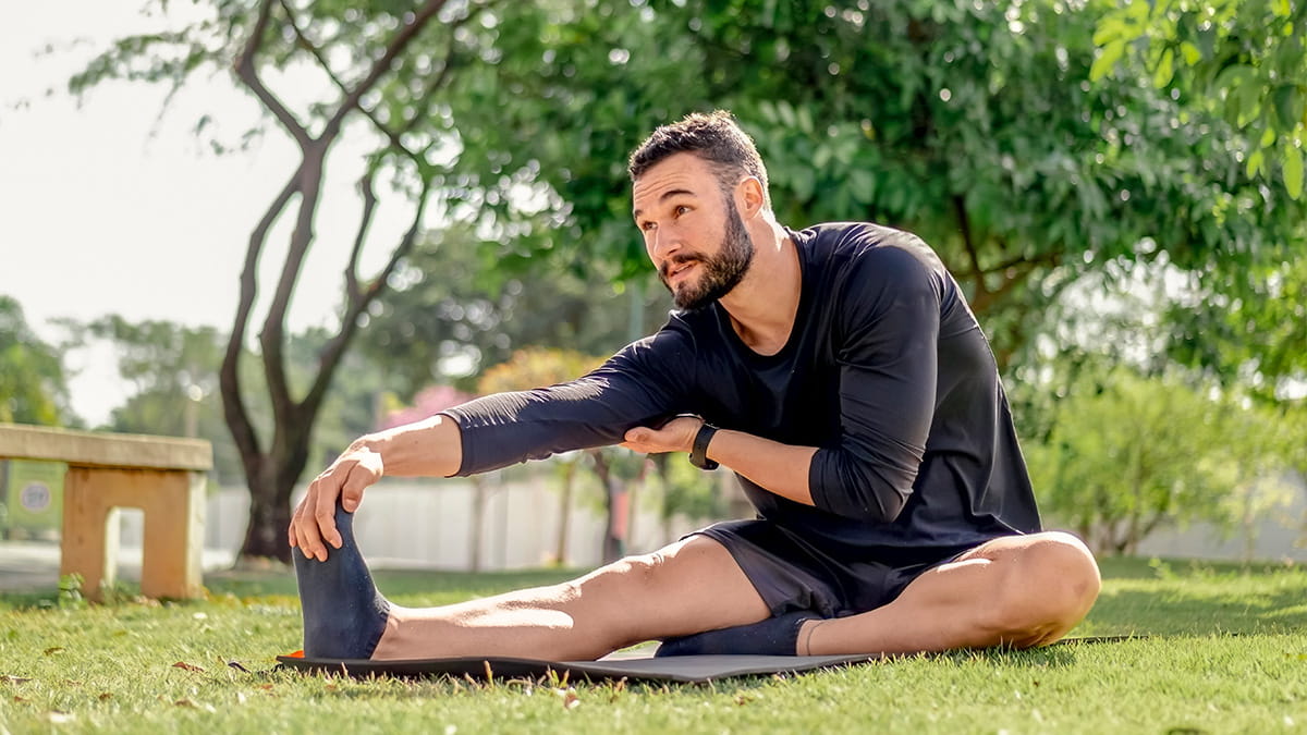Man sitting on the lawn stretching his legs