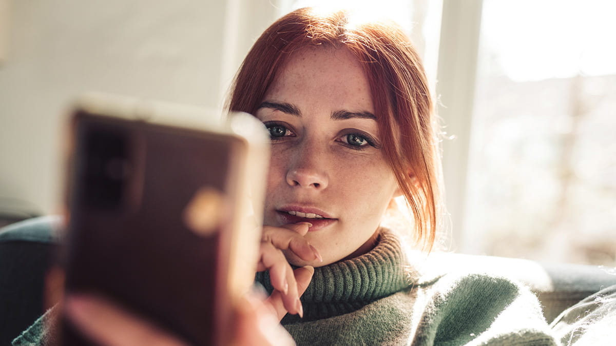 Person reviewing information on a smartphone at home.