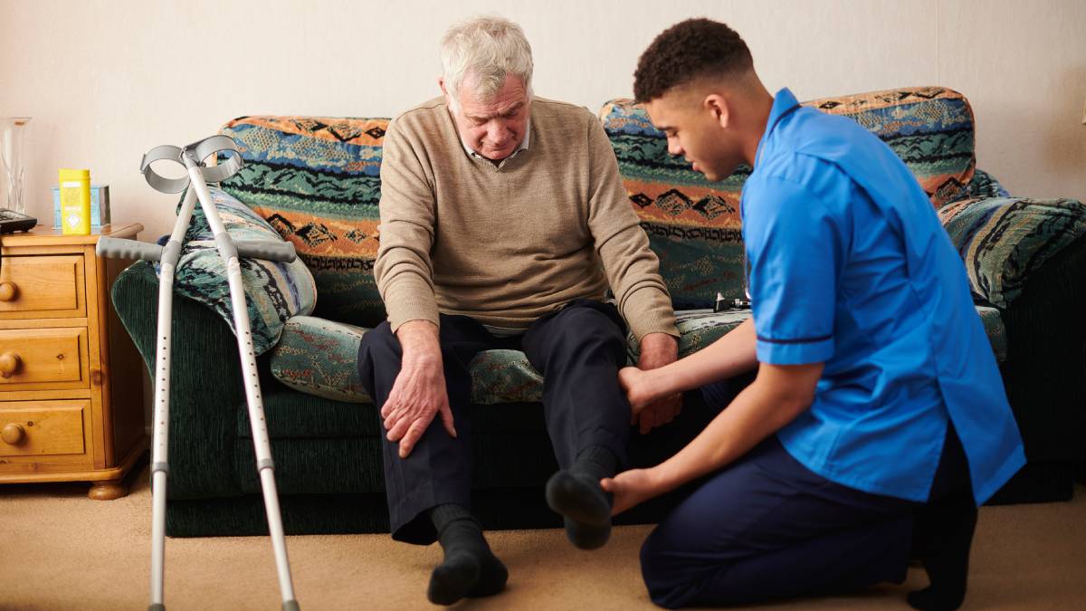 Male physiotherapist working with an elderly male patient on his knee