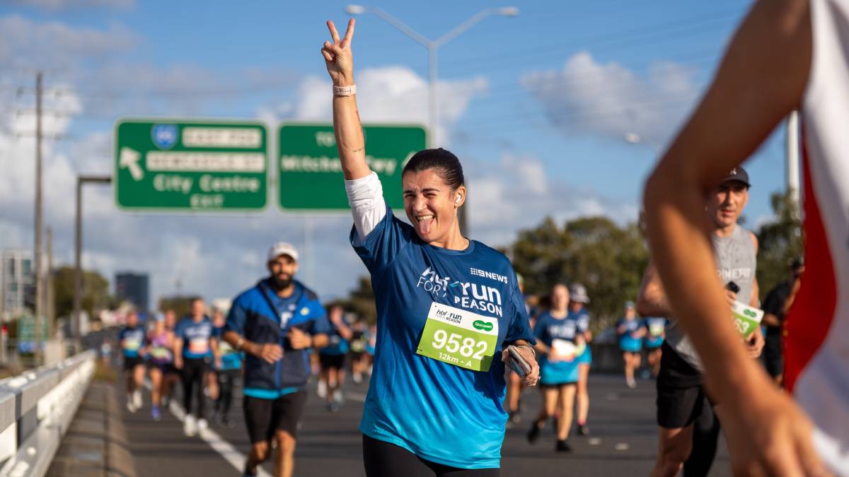 Run for a reason participant giving a peace sign as she runs past