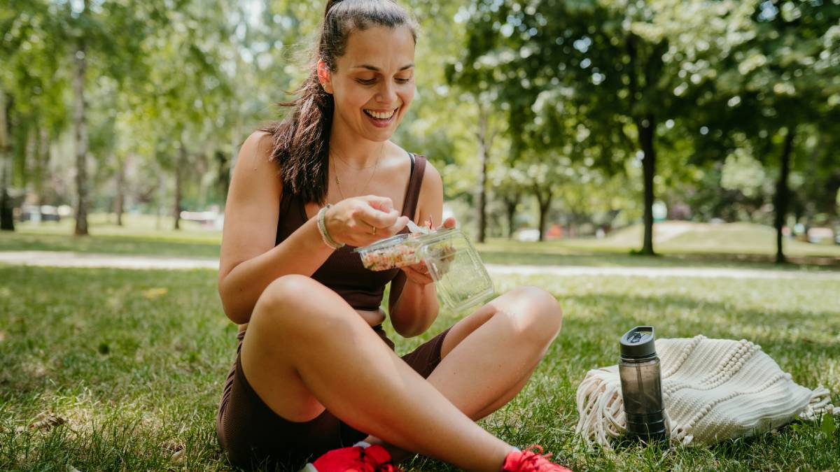 Woman sitting on the grass outside eating her lunch