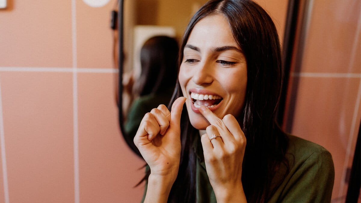 Young woman flossing her teeth in the bathroom