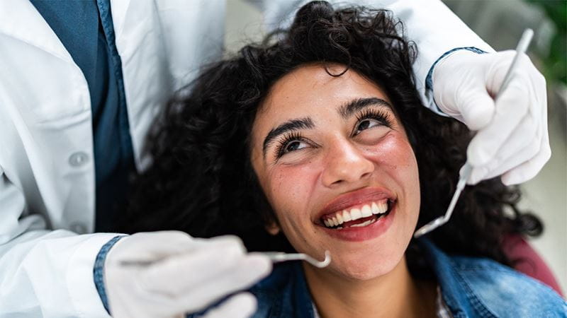 Person having their teeth examined with dental instruments during a dental check-up.