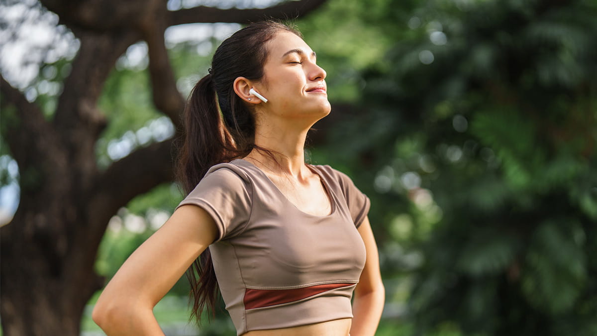 Young female runner with eyes closed and sun on her face