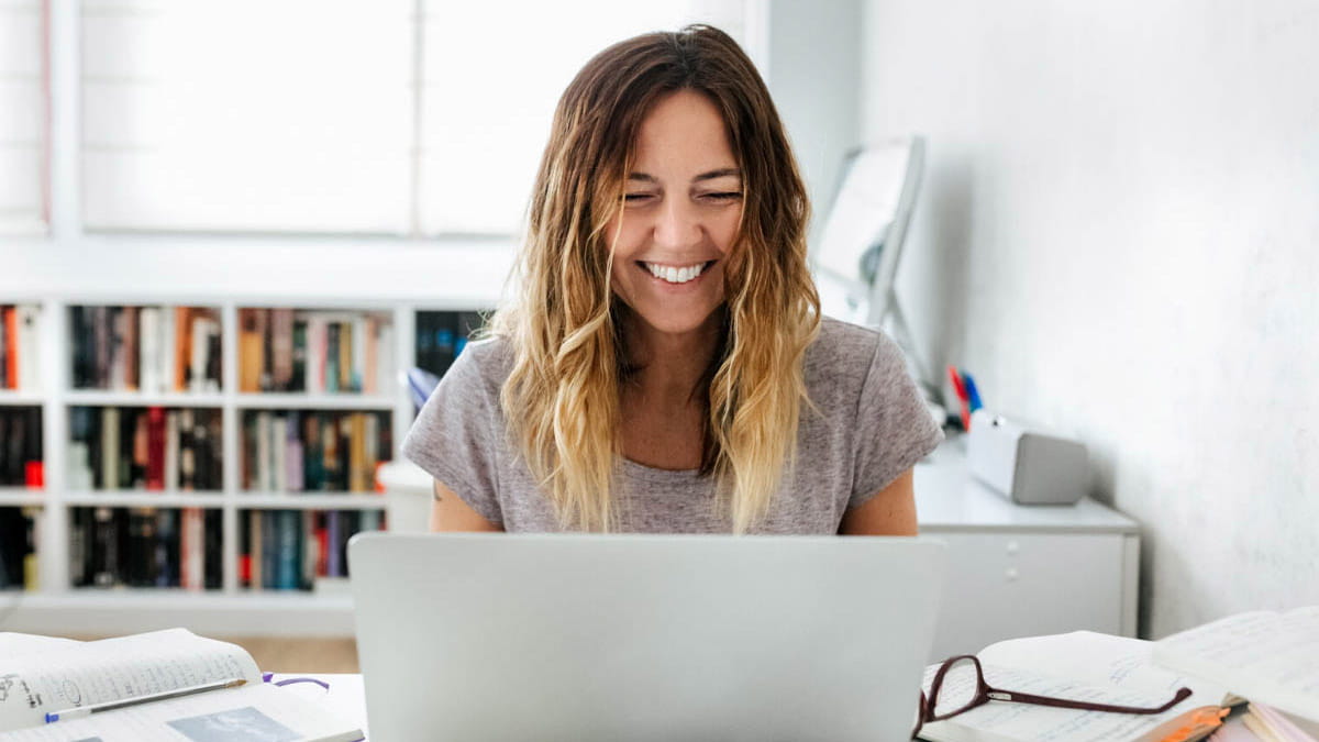 Person smiling while working on laptop