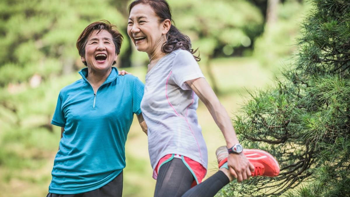 Two older woman stretching after exercise