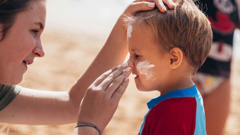 Mum putting sunscreen on toddler son
