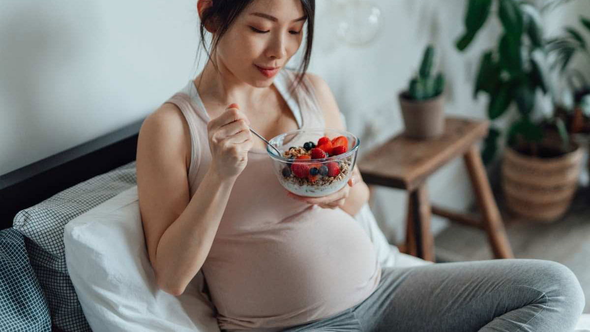 Pregnant woman eating fruit and yoghurt