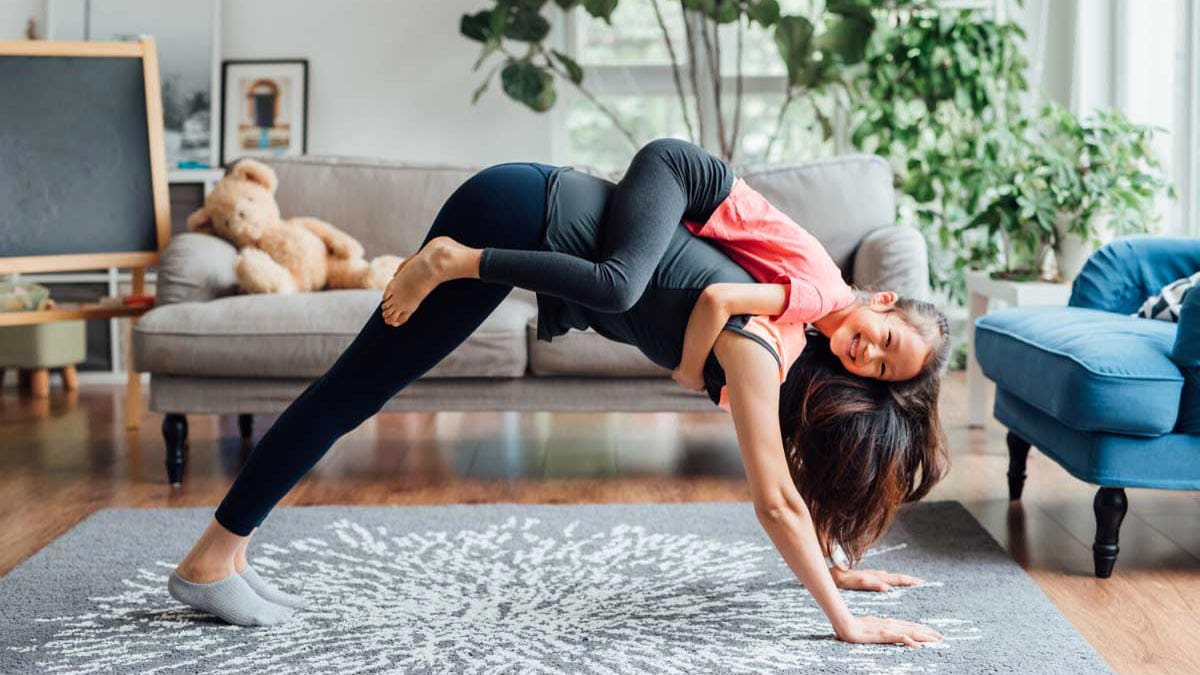 Mum doing downward dog with daughter on her back
