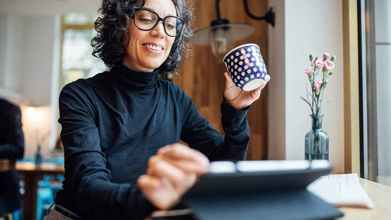 Woman with glasses enjoying reading on laptop