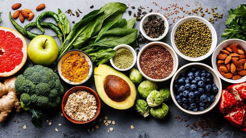 A spread of healthy foods including green vegetables, fruit and avocado