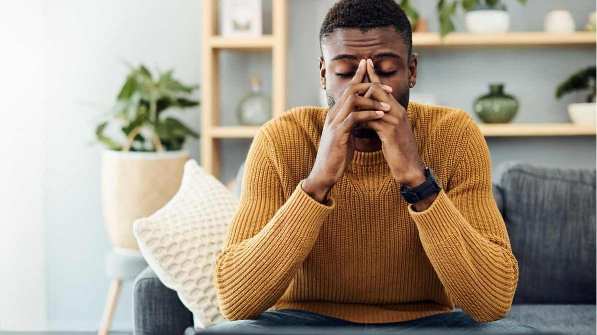 a young man sitting on a couch looking stressed or anxious