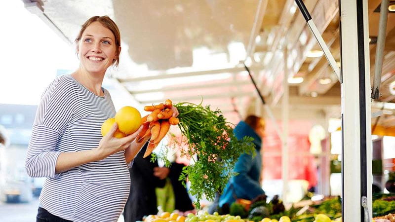 Pregnant woman buying fruit and vegetables
