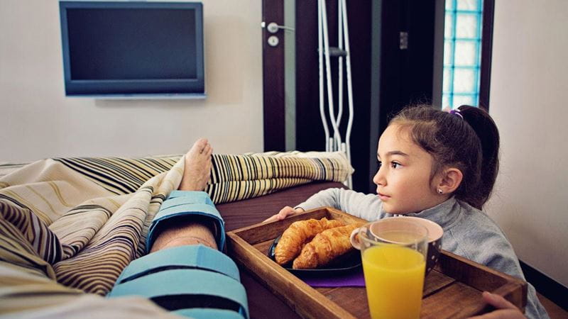 Young daughter visiting dad in hospital after ACL surgery