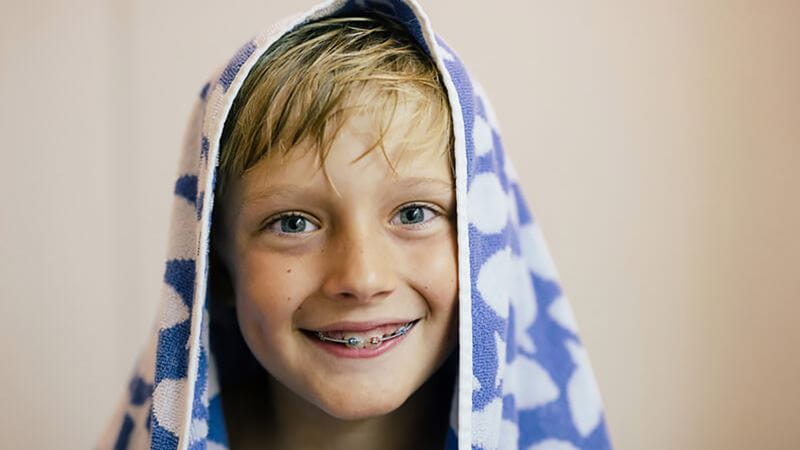 Primary school aged boy with braces smiling after a shower