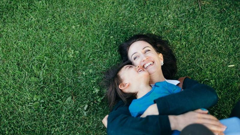 Mother and daughter lying down on grass