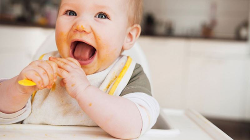 Excited infant enjoying first solid foods