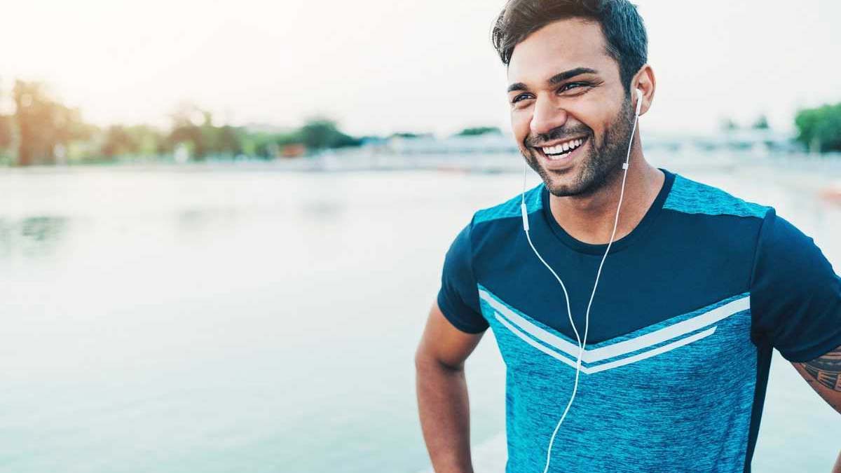A young man smiling after exercise by the water