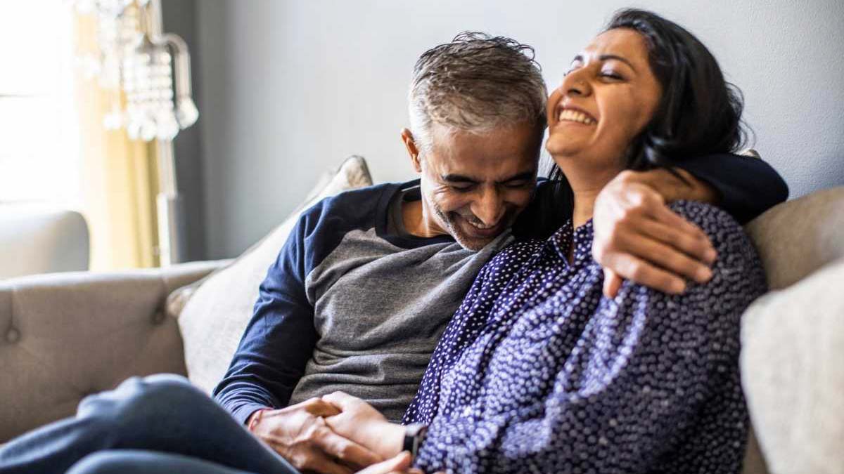A happy couple laughing on a couch