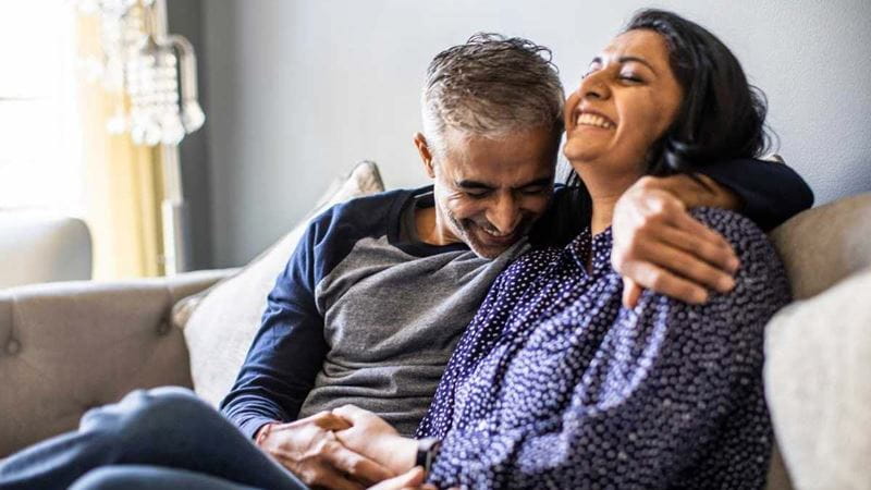 A happy couple laughing on a couch