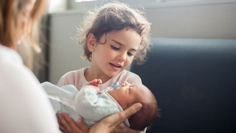 Little girl holding newborn baby